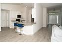 Open-concept kitchen and bar area featuring stone countertops, white cabinetry, and an inviting seating area at 2858 Parlay Ln, North Port, FL 34286