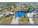 Aerial view of a single-story home with a bright blue metal roof, surrounded by homes, canals and lush landscaping at 3825 Barnegat Dr, Punta Gorda, FL 33950