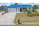 Single-story home featuring a bright blue metal roof, a white garage door and decorative landscaping at 3825 Barnegat Dr, Punta Gorda, FL 33950