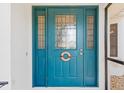 Vibrant turquoise front door with decorative sidelights and transom window, adorned with a nautical 'Welcome Aboard' wreath at 3825 Barnegat Dr, Punta Gorda, FL 33950