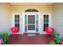 Cozy front porch featuring a gray door, red chairs, and potted plants creating an inviting entrance at 5219 Guava Ter, Port Charlotte, FL 33981