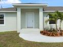 Inviting entryway featuring a covered porch, new white door, and tropical landscaping at 5353 Kaspar St, Port Charlotte, FL 33981