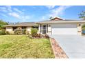Inviting single-story home featuring lush green lawn, brick-lined driveway, and two-car garage at 566 Reading Nw St, Port Charlotte, FL 33952