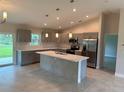 Modern kitchen features gray cabinets, stainless steel appliances, and a large island with a sink at 8667 Lisa Blvd, North Port, FL 34288