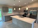 Modern kitchen features gray cabinets, stainless steel appliances, and a large island with a sink at 8667 Lisa Blvd, North Port, FL 34288