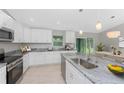 Bright kitchen with white cabinetry, granite countertops, stainless steel appliances, and breakfast bar at 8687 Lisa Blvd, North Port, FL 34288