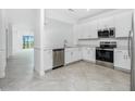 Open kitchen with stainless steel appliances, white cabinets, and tile flooring at 8700 Seasalt Loop, Englewood, FL 34224