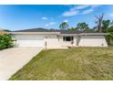 Charming single-story home featuring a two-car garage, manicured lawn, and freshly painted exterior at 1231 Beacon Dr, Port Charlotte, FL 33952
