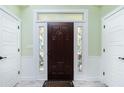 Beautiful dark wooden front door with decorative glass panels, flanked by white trim and sidelights at 13204 Kakapo Ave, Port Charlotte, FL 33981