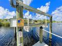 View of a boat lift with a control panel beside a calm canal under a clear blue sky at 13830 Begonia Cir, Port Charlotte, FL 33981