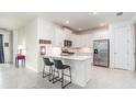 Bright kitchen featuring white cabinets, stainless steel appliances, and a breakfast bar with modern stools at 16965 Hawk Ct, Punta Gorda, FL 33982