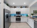 Bright kitchen featuring stainless steel appliances, white cabinetry, granite countertops, and mosaic backsplash at 17857 Woodland Ct, Punta Gorda, FL 33982