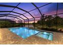 Stunning screened pool with a spa and a picturesque lake view at twilight at 19821 Montenero Way, Venice, FL 34293
