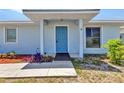 Welcoming front entrance with a bright blue door, neat landscaping, and a convenient walkway at 22299 Laramore Ave, Port Charlotte, FL 33952