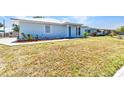 Single-story home showcases light blue siding, a well-manicured lawn, and charming landscaping near the entrance at 22299 Laramore Ave, Port Charlotte, FL 33952