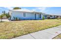 Quaint single-story home featuring a light blue exterior with small decorative garden bed and a concrete walkway at 22299 Laramore Ave, Port Charlotte, FL 33952