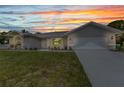 Beautiful one-story home with an attached two car garage, lush green lawn, and a colorful sunset at 229 Waterside St, Port Charlotte, FL 33954