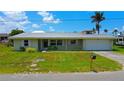 Charming single-story home with a metal roof, well-maintained lawn, and an attached garage in a serene setting at 24239 Yacht Club Blvd, Punta Gorda, FL 33955