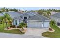 Beautiful home featuring a well-kept lawn, tropical landscaping, and a spacious two-car garage at 24358 Folkstone Ave, Punta Gorda, FL 33980