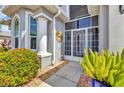 Inviting front entrance with decorative columns, an elegant screen door, and vibrant landscaping at 24358 Folkstone Ave, Punta Gorda, FL 33980