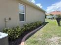 View of side yard, showing green grass and a concrete edging along the back of the home at 25008 Lalique Pl, Punta Gorda, FL 33950