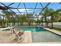 Inviting screened-in pool area, complete with spa, rocking chairs, and travertine tile decking at 2515 Sherman Oak Dr, North Port, FL 34289