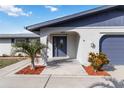 Inviting front entrance with a decorative glass door, arched entryway, and tropical landscaping at 711 Forest Hill Nw Ln, Port Charlotte, FL 33948