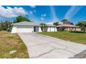 Exterior view of home featuring driveway, two-car garage, and tropical landscaping in the front yard at 891 Bayard St, Port Charlotte, FL 33948