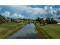 Scenic backyard view featuring a serene canal, green landscaping, and neighboring houses at 1 Sportsman Cir, Rotonda West, FL 33947