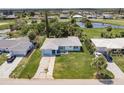Aerial view of a light blue single-story home with a large green lawn and mature landscaping near a pond at 37 Oakland Hills Ct, Rotonda West, FL 33947