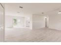 Expansive living room features light wood-look flooring, neutral walls, and sliding glass doors to the outdoors at 37 Oakland Hills Ct, Rotonda West, FL 33947