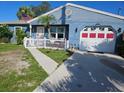 Quaint single-story blue house with a red and white garage door and a white picket fence at 4583 S Salford Blvd, North Port, FL 34287