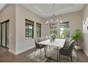 Elegant dining room with a modern chandelier, marble table, and large windows offering a serene view at 5451 Prime Ter, North Port, FL 34286