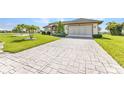 Patterned driveway leading to an attached garage complementing the manicured lawn and tropical landscaping at 1499 Nuremberg Blvd, Punta Gorda, FL 33983