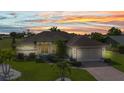 Sunset view of a well-maintained home boasts manicured lawn, decorative landscaping, and a brick driveway at 1499 Nuremberg Blvd, Punta Gorda, FL 33983