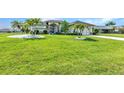 Expansive front yard with well-maintained lawn and mature palms surround a home with brick driveway and neutral color palette at 1499 Nuremberg Blvd, Punta Gorda, FL 33983