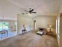 Inviting living room with neutral tones and a ceiling fan, seamlessly connected to the dining area at 18335 Oxford Ave, Port Charlotte, FL 33948