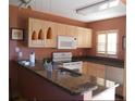 Well-lit kitchen with granite countertops, modern appliances, and bright, natural wood cabinets at 25050 Sandhill Blvd # A2, Punta Gorda, FL 33983