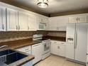 Bright kitchen featuring white cabinets, modern appliances and a mosaic backsplash at 3300 Loveland Blvd # 602, Punta Gorda, FL 33980