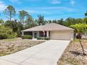 Inviting single-story home with a large driveway, lush green landscaping, and a charming front porch at 3322 Hampton St, Port Charlotte, FL 33948