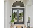 Elegant front door with a transom window, complemented by decorative plants and a 'Welcome' mat at 3393 S Haberland Blvd, North Port, FL 34288