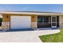 Lovely home exterior featuring stone accents, an attached garage, and a screened in porch at 444 Edgewood Rd, Venice, FL 34293