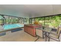 Covered patio featuring a hot tub, outdoor dining area, and a view of the sparkling screened-in pool and lush greenery at 4511 Wilkinson Rd, Sarasota, FL 34233