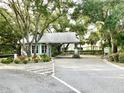Community entrance with gatehouse and gate arm, surrounded by lush landscaping and trees at 1431 Red Oak Ln, Port Charlotte, FL 33948