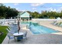 Community pool with many lounge chairs and umbrellas near the pool house on a sunny day at 1431 Red Oak Ln, Port Charlotte, FL 33948