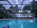 Relaxing pool area featuring a screened enclosure and serene water views with palm trees at 17150 Sarong Ln, Punta Gorda, FL 33955