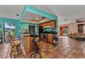 Open kitchen featuring warm wood cabinets, stainless steel appliances, breakfast bar and earth tone floors at 2031 Backton St, Port Charlotte, FL 33948