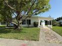 Front view of single-story home with a carport and mature trees providing shade at 21899 Cellini Ave, Port Charlotte, FL 33952