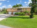 Spacious two-story home boasting a two-car garage and lush green lawn, enhanced by mature palm trees at 24398 Treasure Island Blvd, Punta Gorda, FL 33955