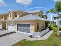 A charming yellow townhome with a well-kept lawn, featuring a gray garage door and a welcoming, landscaped exterior at 25555 Heritage Lake Blvd # 27, Punta Gorda, FL 33983